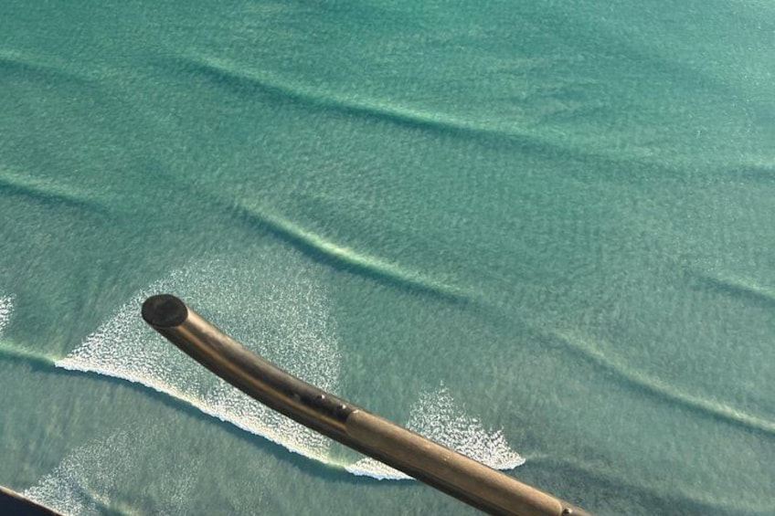 A wooden boat on turquoise water with gentle waves. 4