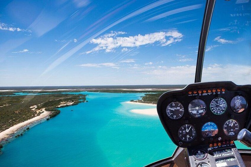 Vista desde la cabina con cielo despejado, mar turquesa y una línea costera. 2