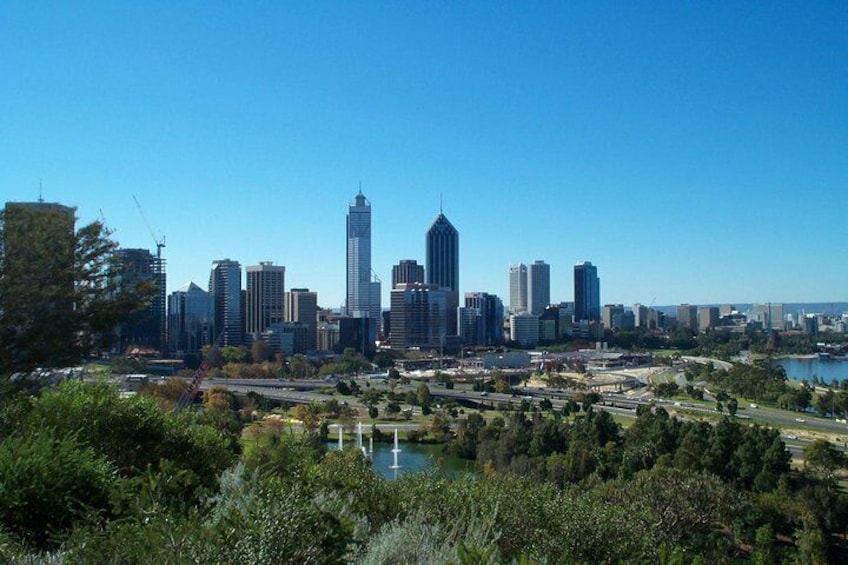 A city skyline with modern skyscrapers, a river, and surrounding greenery. 1