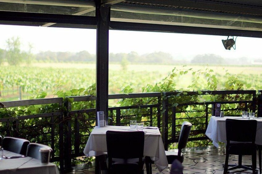 An outdoor dining area with tables and chairs, overlooking a green field. 4