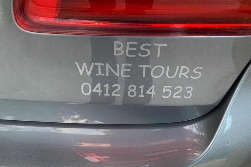 À l'arrière d'une voiture, on peut voir un autocollant sur lequel est écrit : « MEILLEURES VISITES DE VIGNOBLES 0412 814 523 ». 5