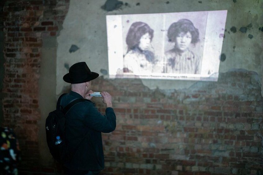 A person taking a photo of a poster on a brick wall. 2