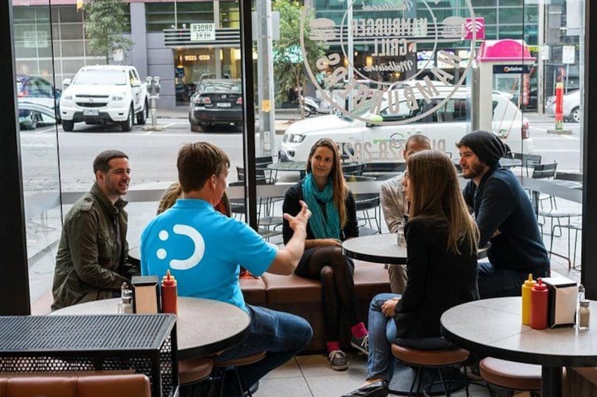 A group of people sitting at tables outside a cafe, engaged in conversation. 2
