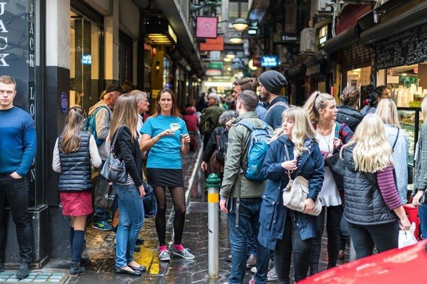 En livlig gade med folk, der står og går, butikker langs begge sider, og en smal gyde. 5