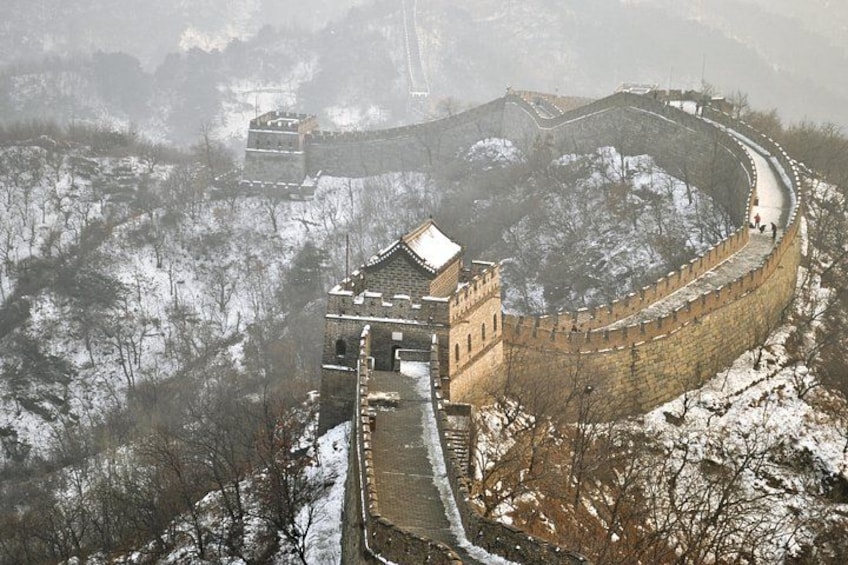 The Great Wall of China winding through a snowy landscape with a watchtower and a pagoda. 1