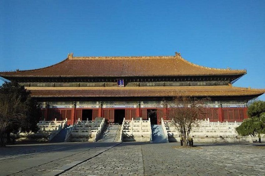 A traditional building with a tiled roof and red walls, a staircase leading to the entrance, and a clear blue sky. 5