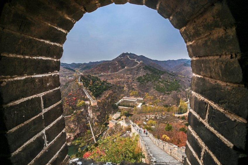 A view through an ancient brick archway overlooking a mountainous landscape with a river and traditional buildings. 4