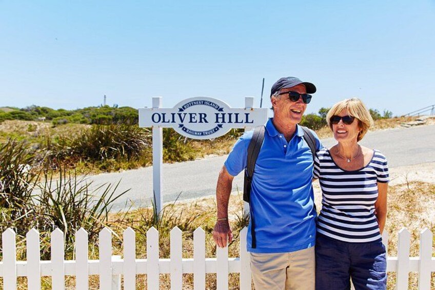 A signpost with 'Oliver Hill' written on it, a white picket fence, and a clear sky. 3