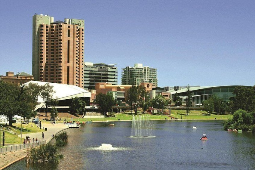 Un lago con una fuente, rodeado de edificios y árboles. 3