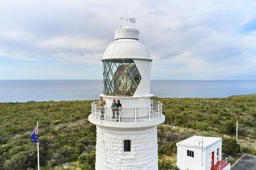 A lighthouse with a white exterior, a glass lantern room, and a flagpole with the Australian flag. 2