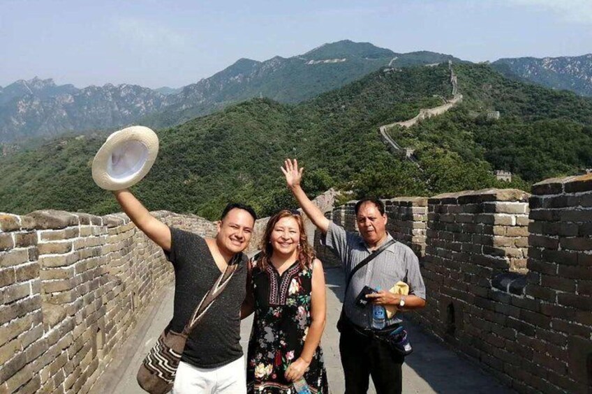 Three people standing on the Great Wall of China with a mountainous landscape in the background. 2