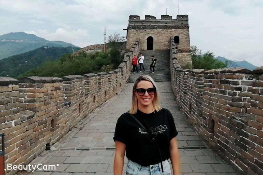 A person standing on the Great Wall of China with a view of the wall and mountains in the background. 1