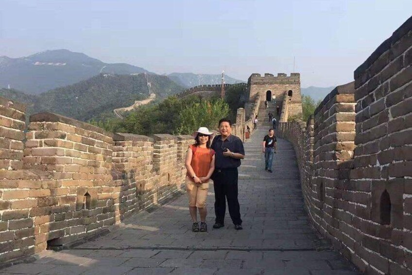 A couple standing on the Great Wall of China with mountains in the background. 4