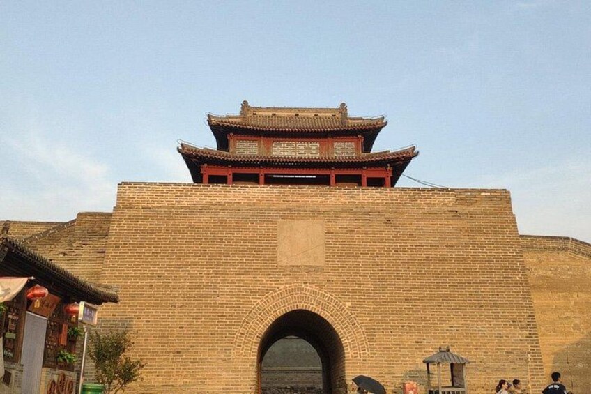 A traditional Chinese gate with a tiled roof and brick walls. 3