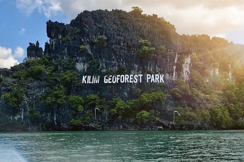A rugged cliff with dense greenery and the text 'Kilim Geoforest Park' on it. 2