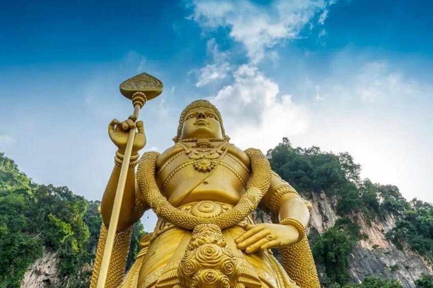 Une grande statue dorée représentant une divinité tenant un bâton, le tout se détachant sur un paysage montagneux. 4