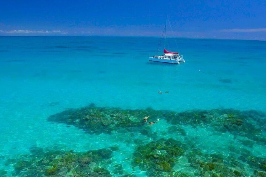 Mar azul transparente con un barco y arrecifes de coral visibles. 1