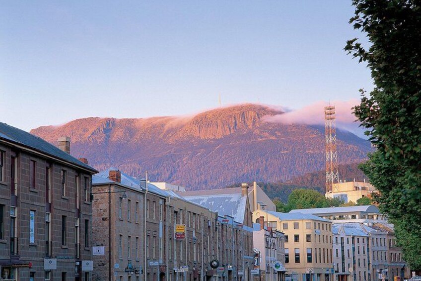 A city street with buildings, a mountain in the background, and a tower. 2