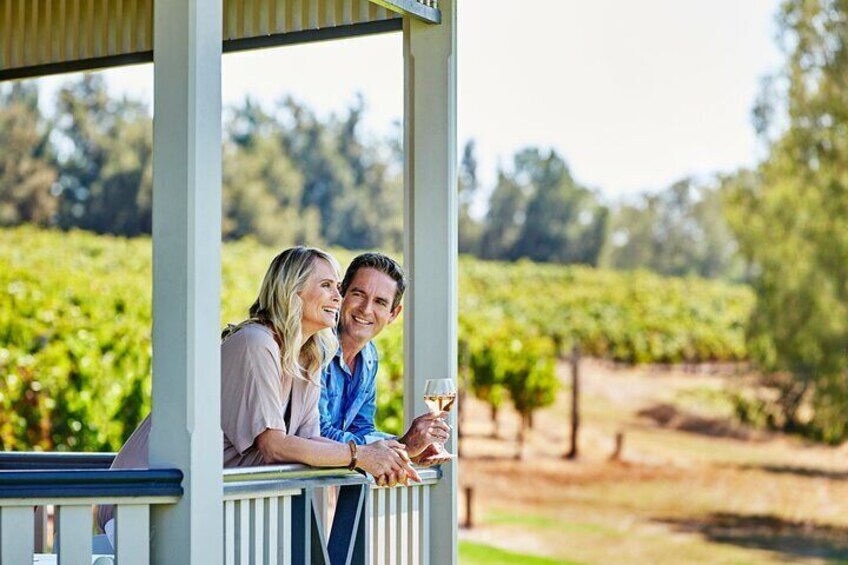 A couple sitting on a porch overlooking a vineyard. 3