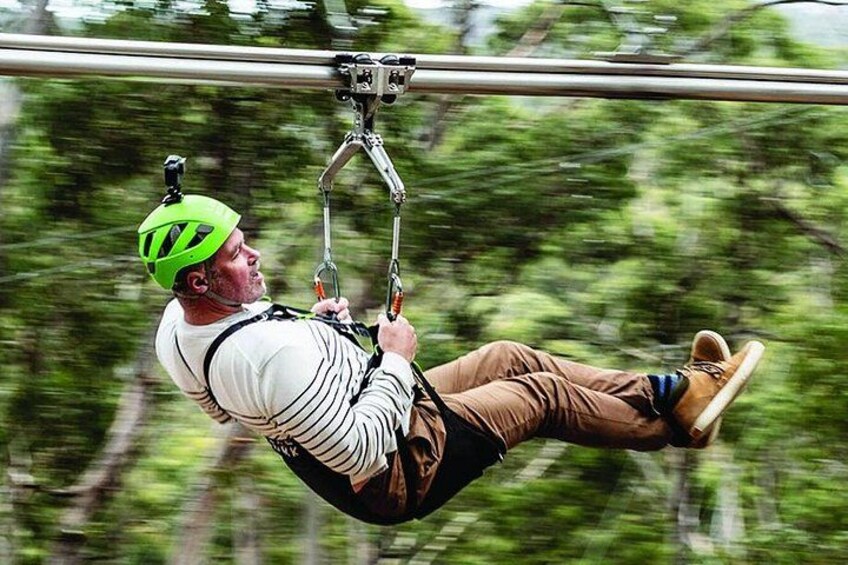 A person suspended in mid-air, wearing a helmet and harness, holding onto a bar. 1