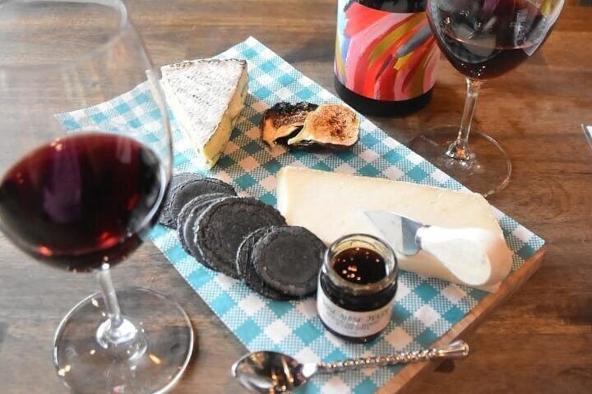A cheese board with crackers, a slice of cheese, and a jar of jam on a checkered napkin. 3