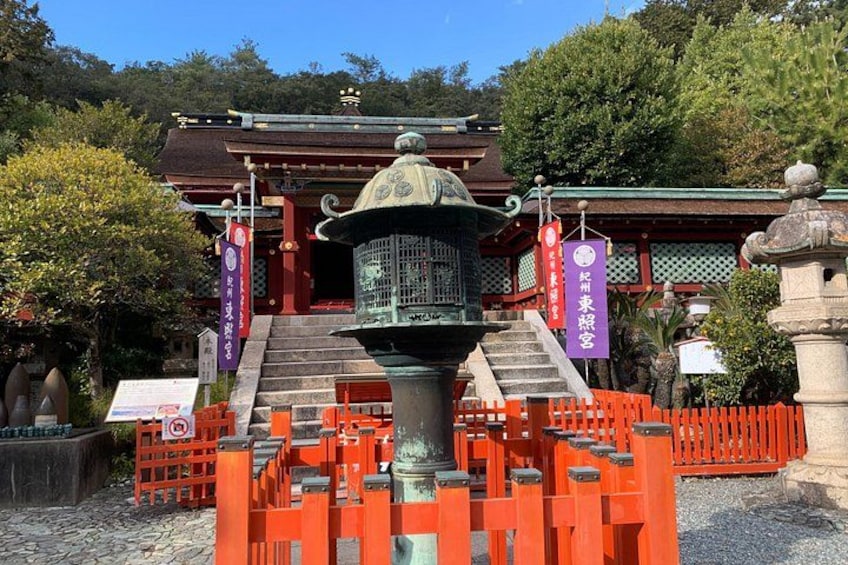 A traditional Japanese temple with a stone lantern, red torii gate, and a staircase leading to the entrance. 3