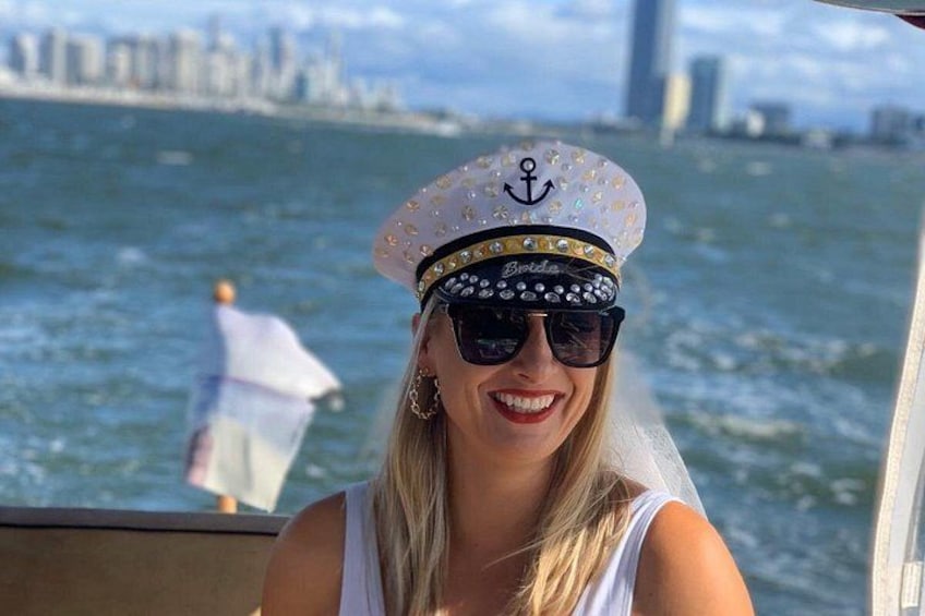 A person wearing a sailor's hat with an anchor emblem, a white dress, and a veil. 1