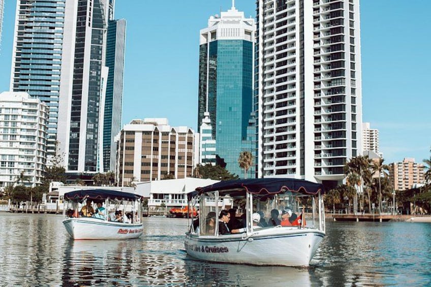 Two boats on a calm water body with tall buildings in the background. 3