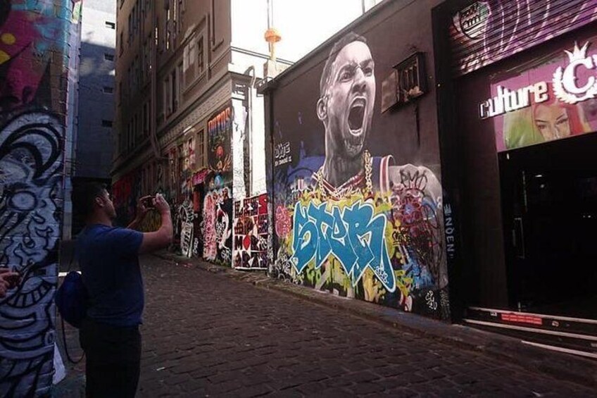 A street with graffiti on the walls and a person taking a photo. 5