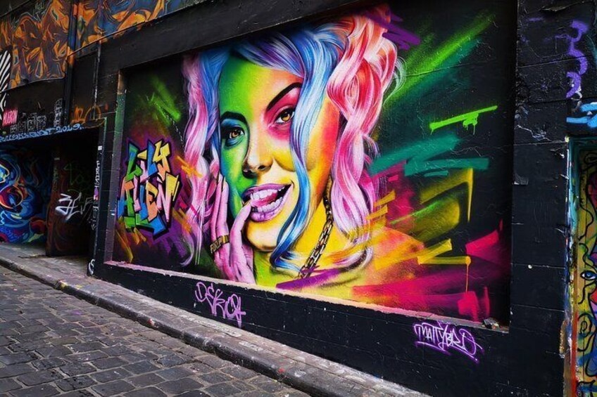 A colorful mural on a building wall with graffiti tags. 1