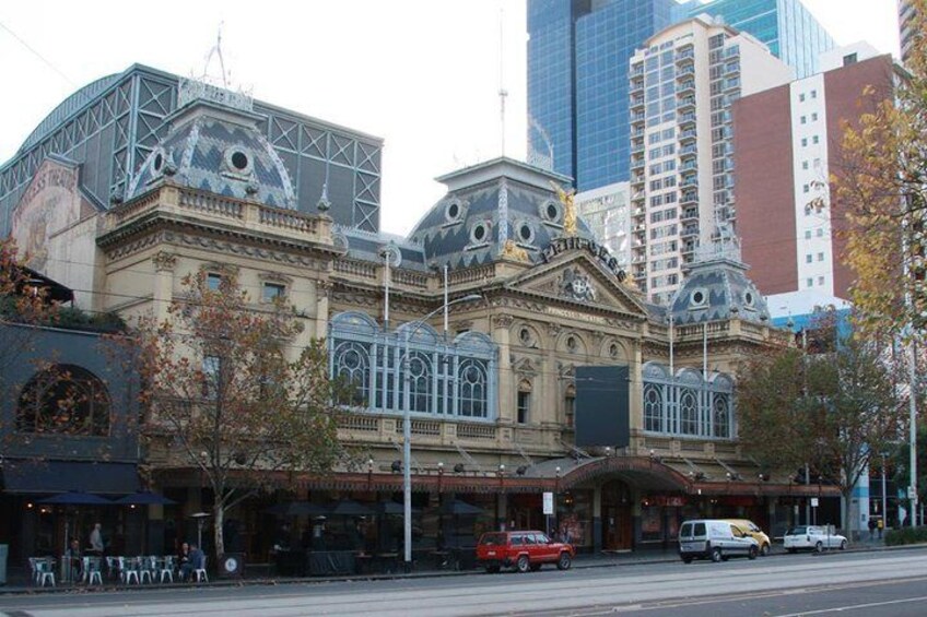 A historic building with ornate architecture, including domes and decorative elements, surrounded by modern high-rise buildings. 3