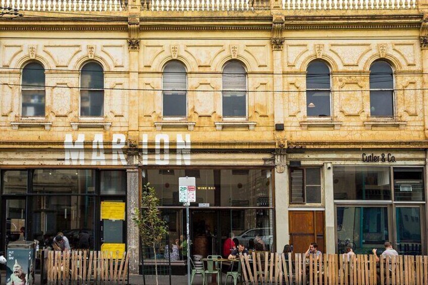 A building with 'MARION' and 'Cutler & Co.' signs, wooden fence, and people sitting outside. 2