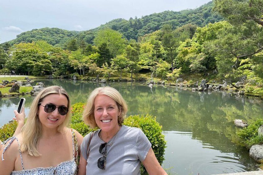 Dos personas junto a un lago tranquilo rodeado de vegetación exuberante y colinas. 2