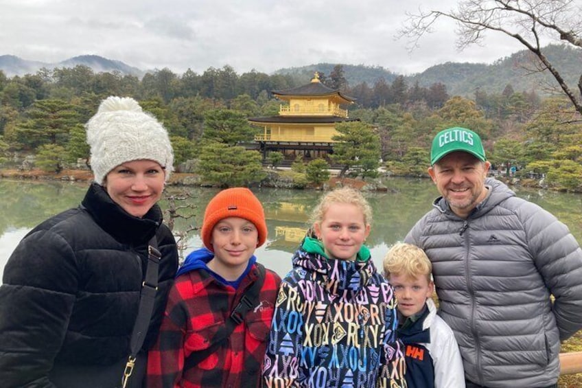 Eine vierköpfige Familie vor einem traditionellen japanischen Gebäude an einem See. 1