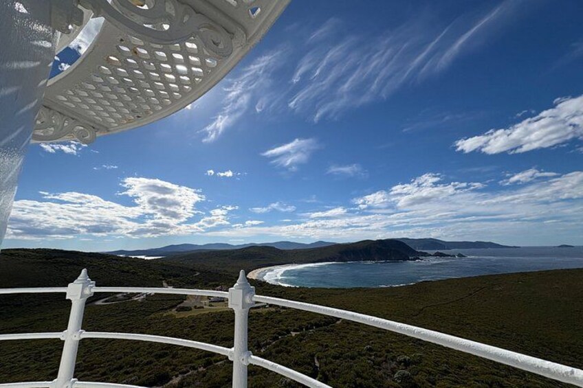 A coastal landscape with a white fence, a clear sky, and distant mountains. 1