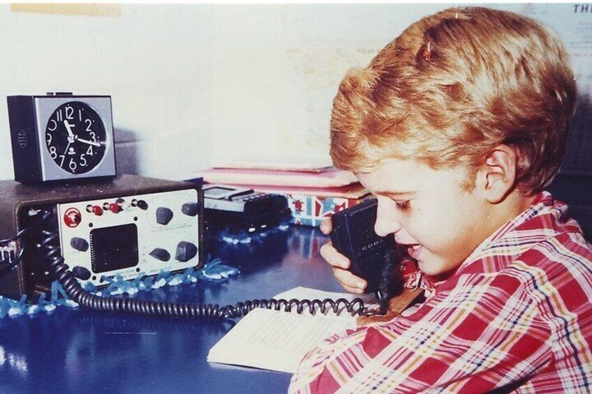 A person using a telephone, a clock, and a notebook on a desk. 3