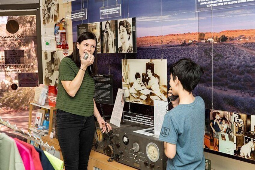 A person speaking into a microphone at a booth with a backdrop of photographs and text. 4