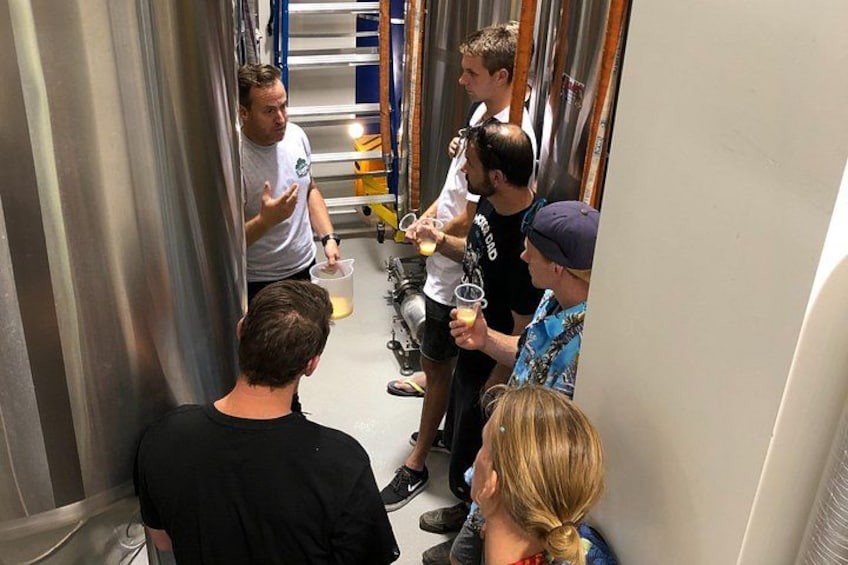 Un groupe de personnes se trouve dans un espace industriel étroit, caractérisé par des structures et des équipements métalliques. 2