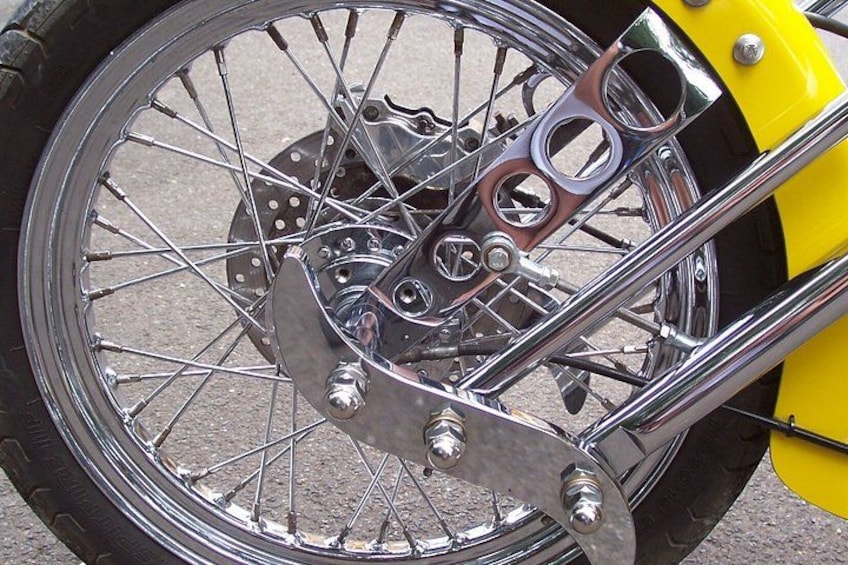 A motorcycle wheel with chrome spokes and a yellow fender. 2