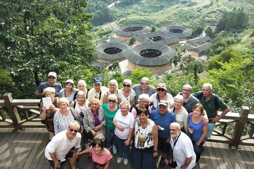 A group of people on a wooden deck overlooking a vineyard with circular buildings. 1