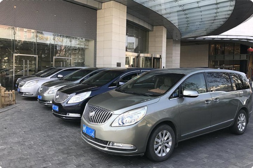 A row of parked cars in front of a building with a curved glass roof. 2