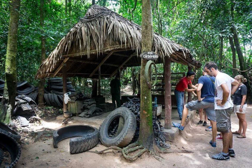 A rustic hut with tires and a sign reading "MIA CATDEPAD" in a forested area. 3
