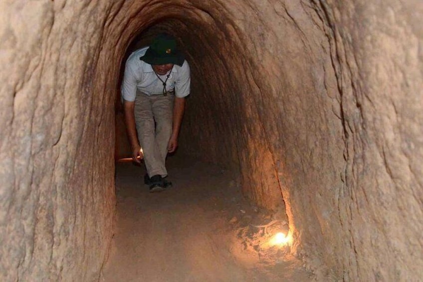 A person walking through a narrow, rocky tunnel. 4