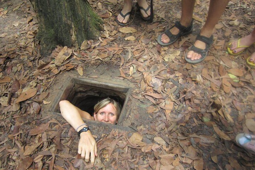 A person peeking out of a hole in the ground surrounded by dry leaves. 5