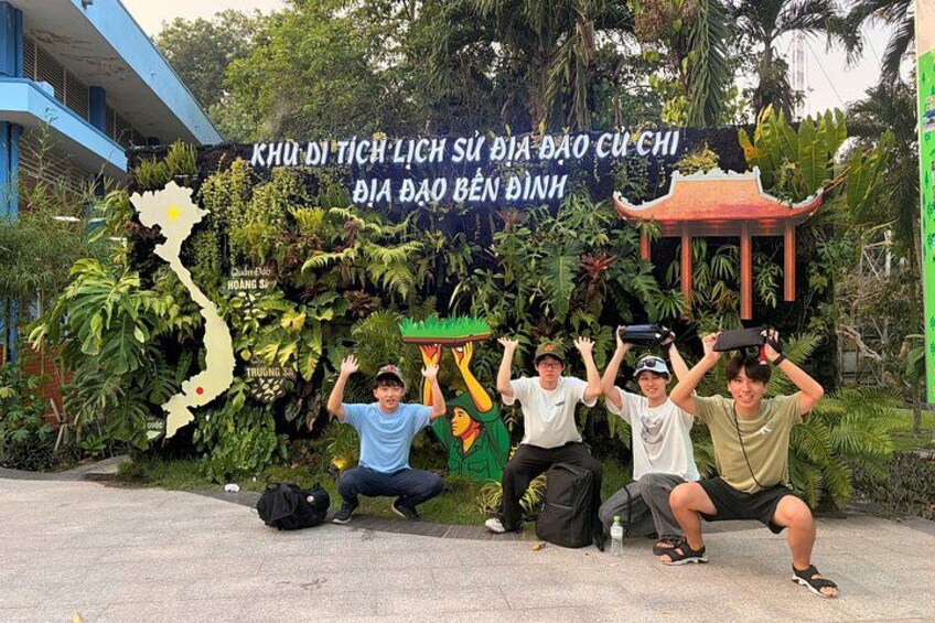 Un grupo de personas posando frente a un mapa y un cartel con texto vietnamita. 5