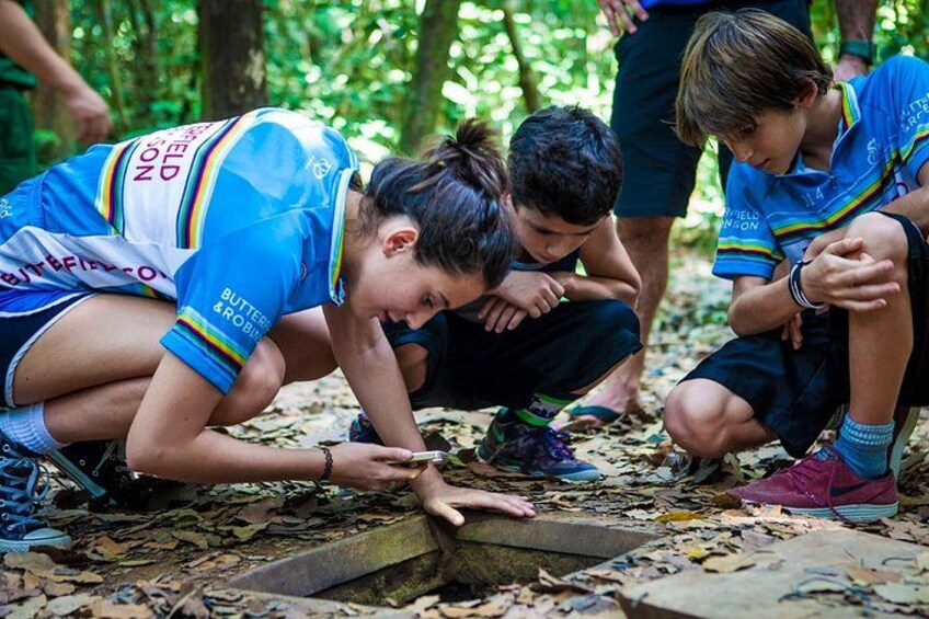 People crouching on forest floor, examining a fallen tree. 4