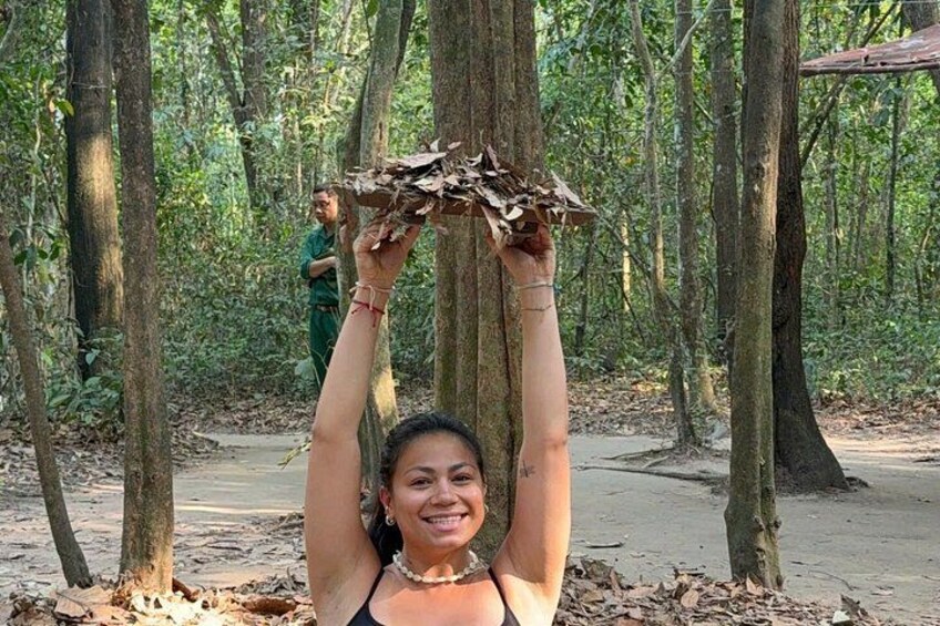 A person holding a branch in a forested area with trees and a dirt path. 2