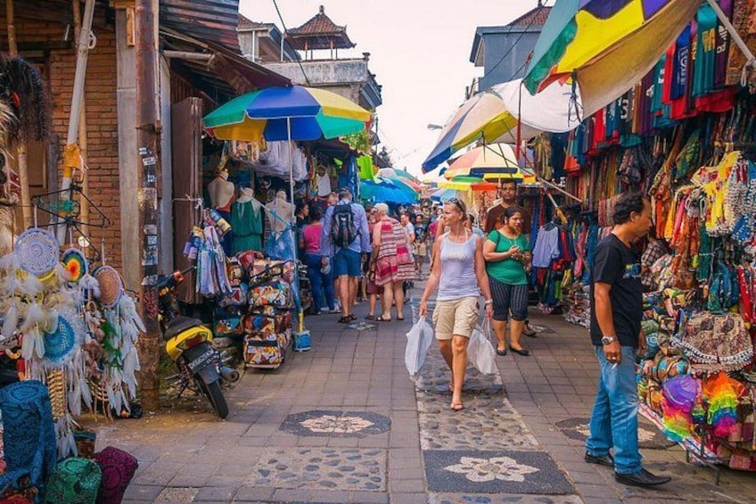 A bustling outdoor market with various stalls selling colorful textiles and accessories. 2