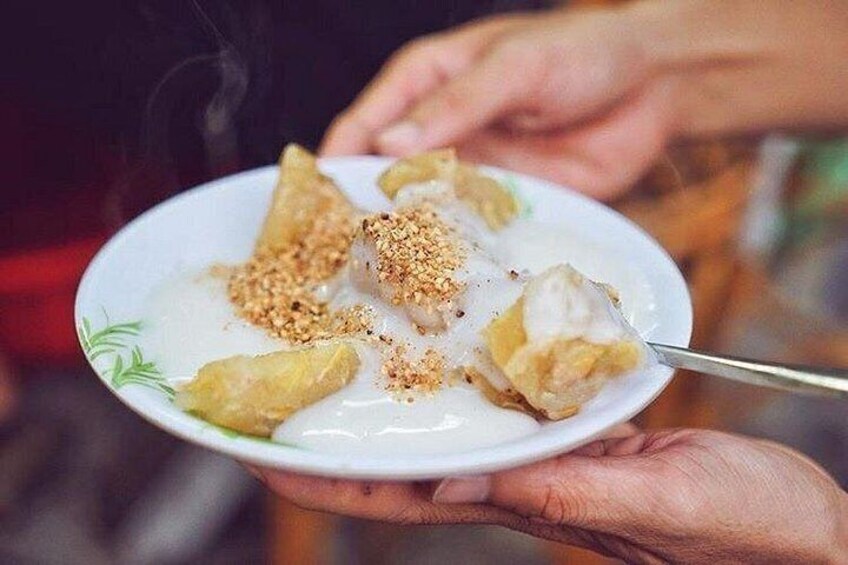 A person holding a plate with dumplings and a spoon. 5
