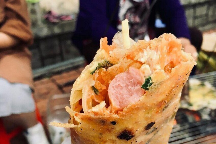 A food item, possibly a wrap, with visible ingredients like sausage and greens. 3